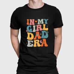 A man wearing a black shirt that says in my girl dad era.