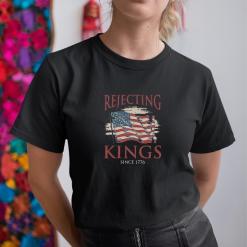 A woman wearing a black shirt that says rejecting kings since 1776.